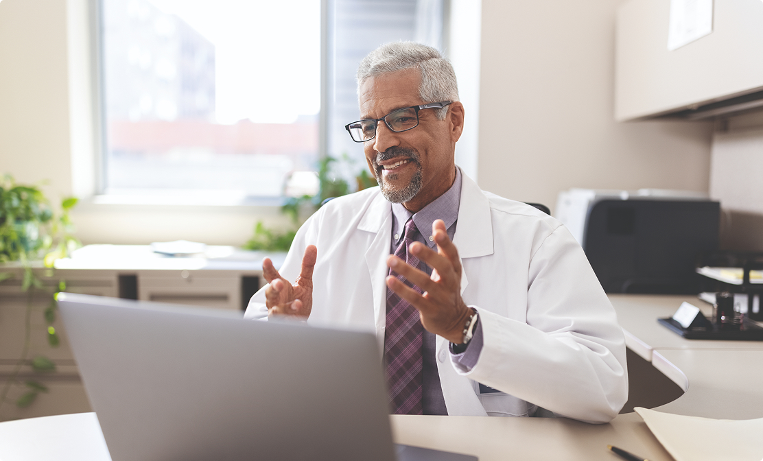 Smiling doctor in virtual meeting on laptop.