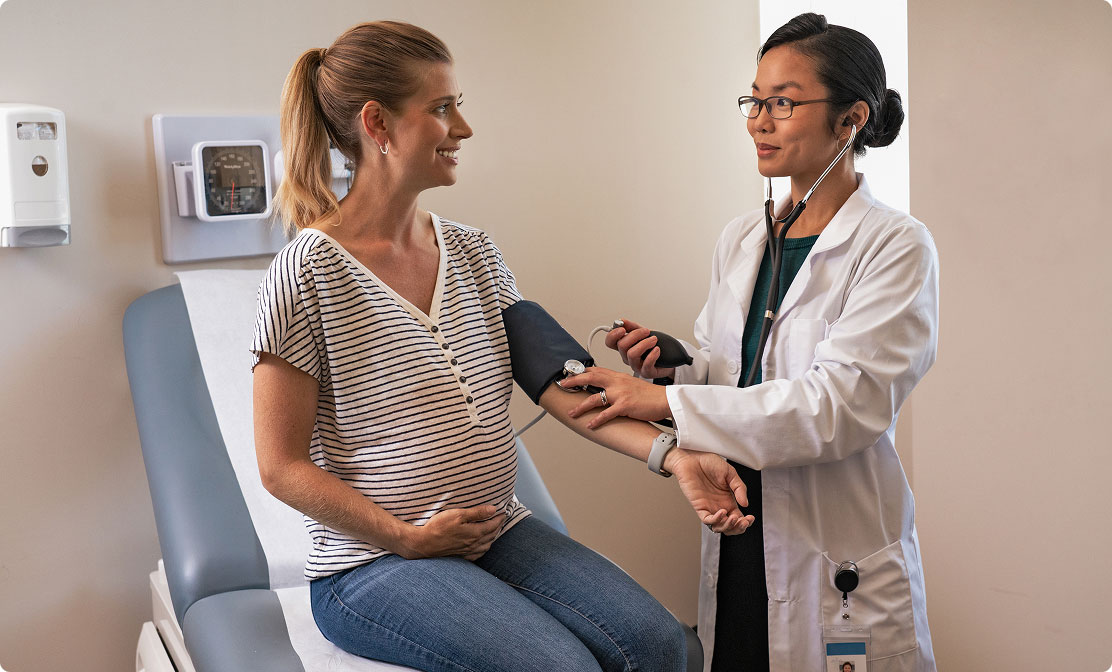 Doctor checking a pregnant woman's blood pressure.