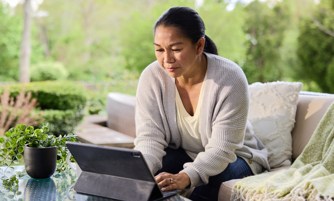 Woman sitting on an outdoor couch using a tablet computer