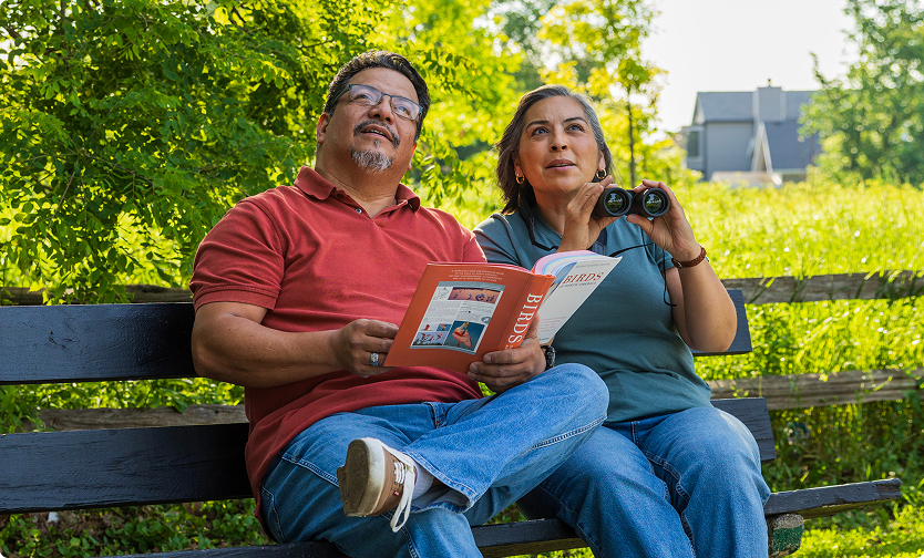 Couple birdwatching on a park bench.